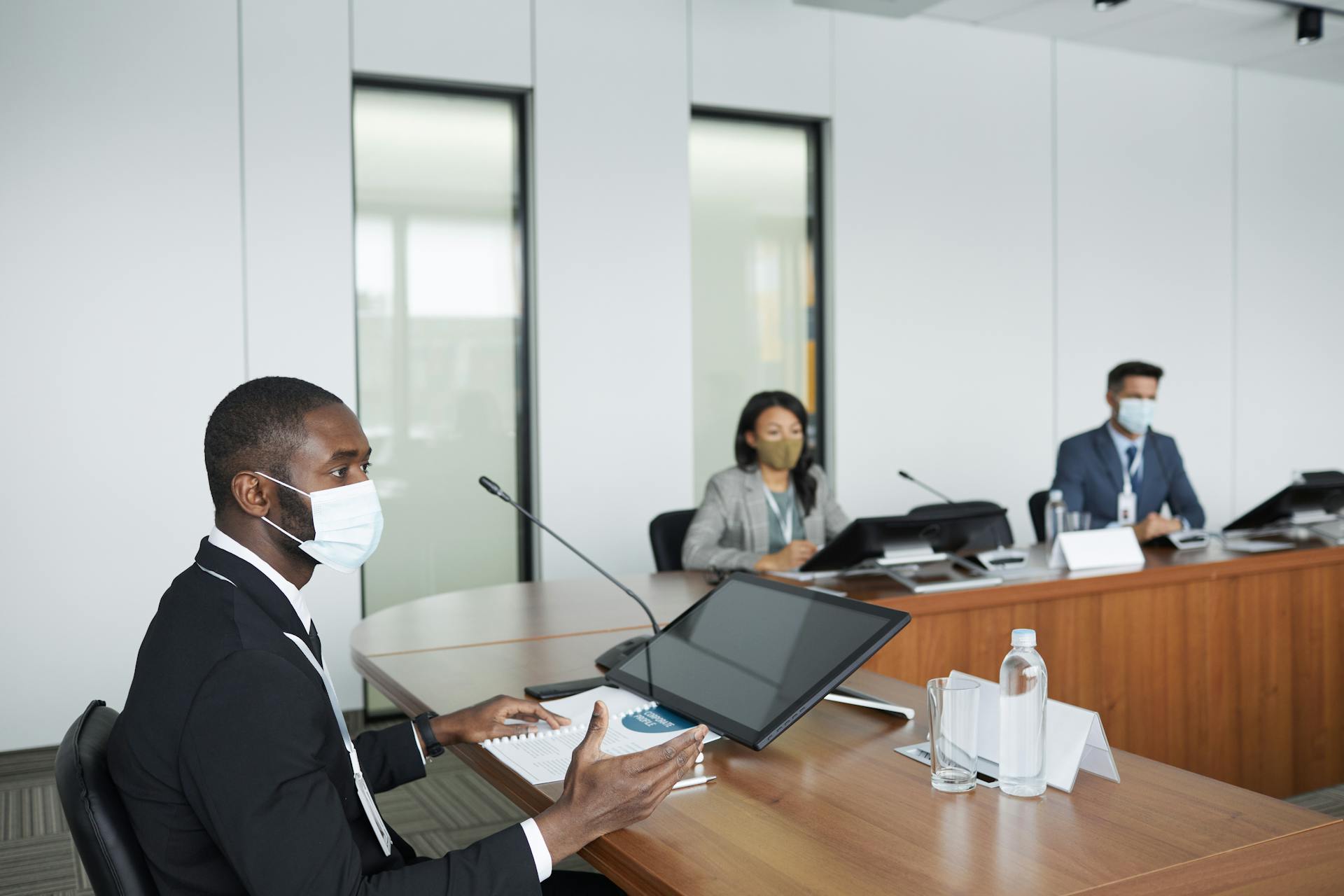 Professionals in face masks hold a business meeting in a modern conference room.