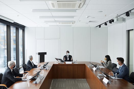 Business professionals in a conference room meeting wearing masks, emphasizing diversity and cooperation.