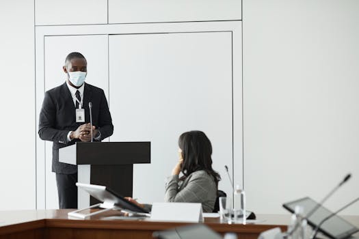 Speaker in mask presenting during a business conference meeting indoors.
