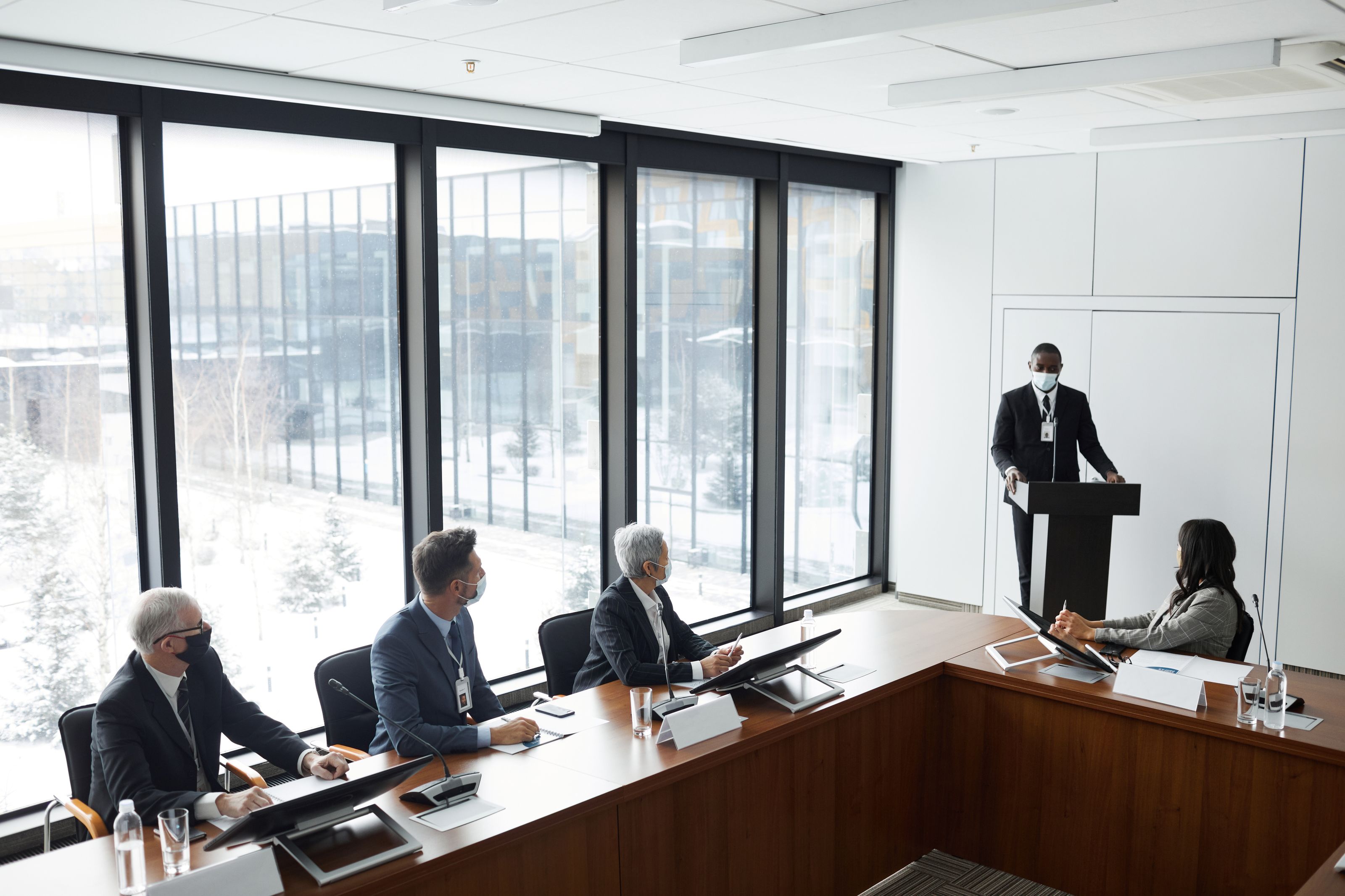 Corporate meeting with diverse professionals wearing masks for safety during pandemic.