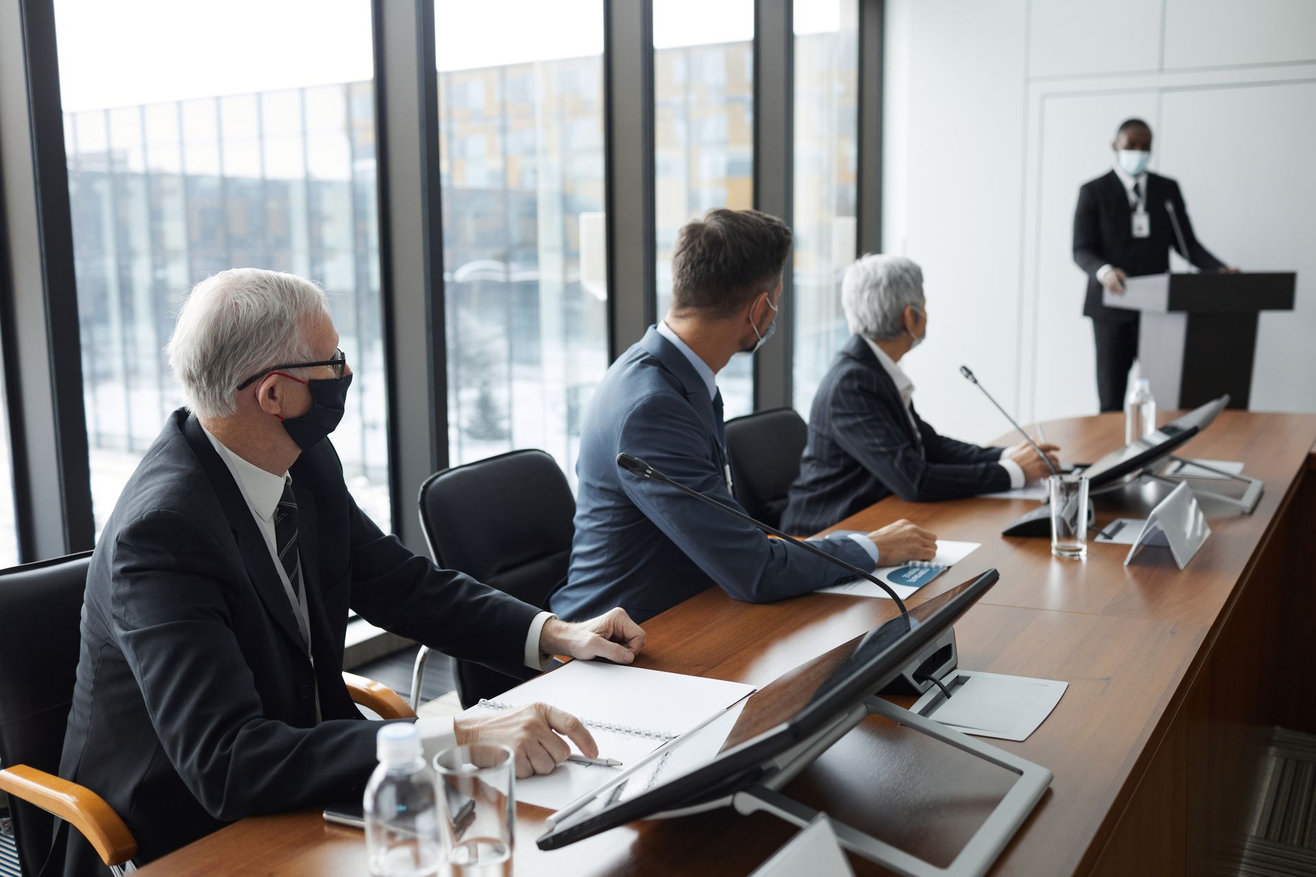Business professionals discussing in a conference room with safety measures like face masks.