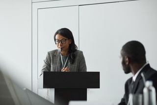 Executive delivering remarks at a conference podium — photo by Werner Pfennig on Pexels