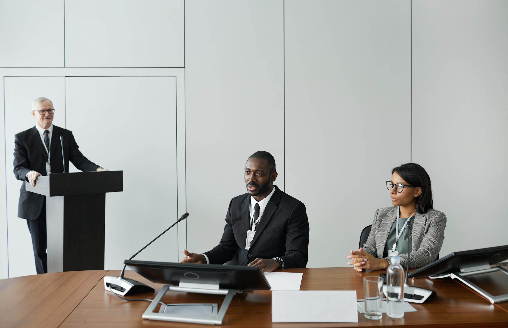 Colleagues in corporate attire discussing at a business meeting indoors.