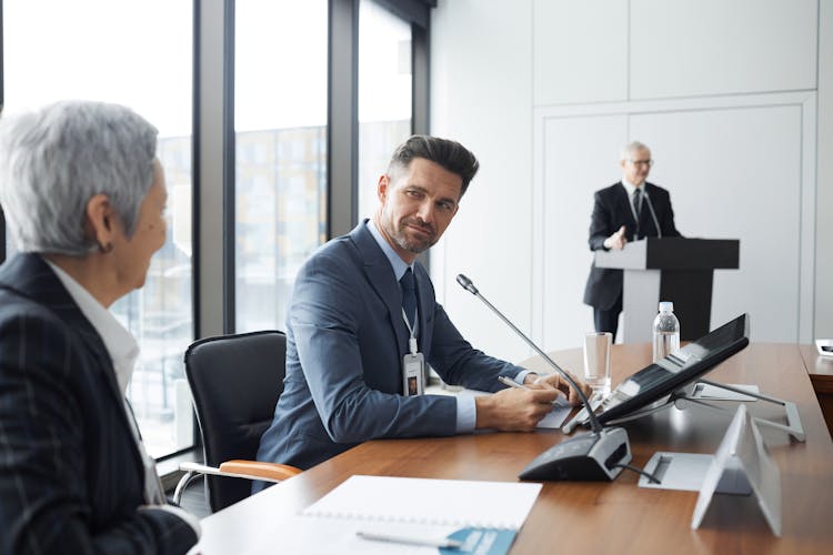 Man And An Elderly Woman Looking At Each Other In A Conference Room 