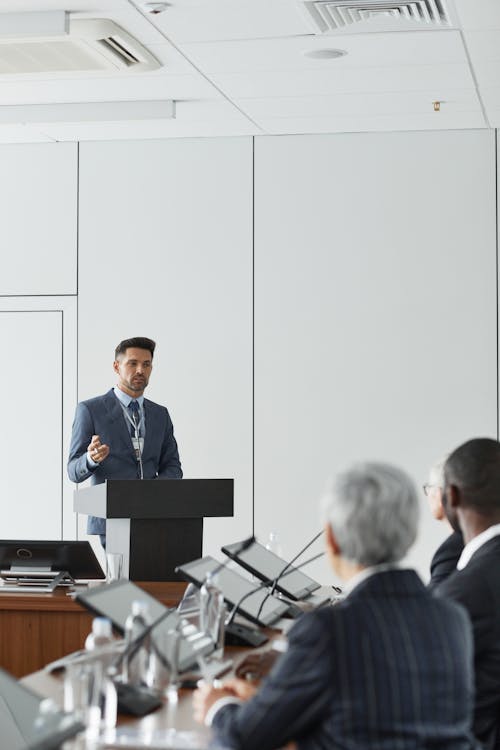 Man Standing Next to a Podium in a Conference Room