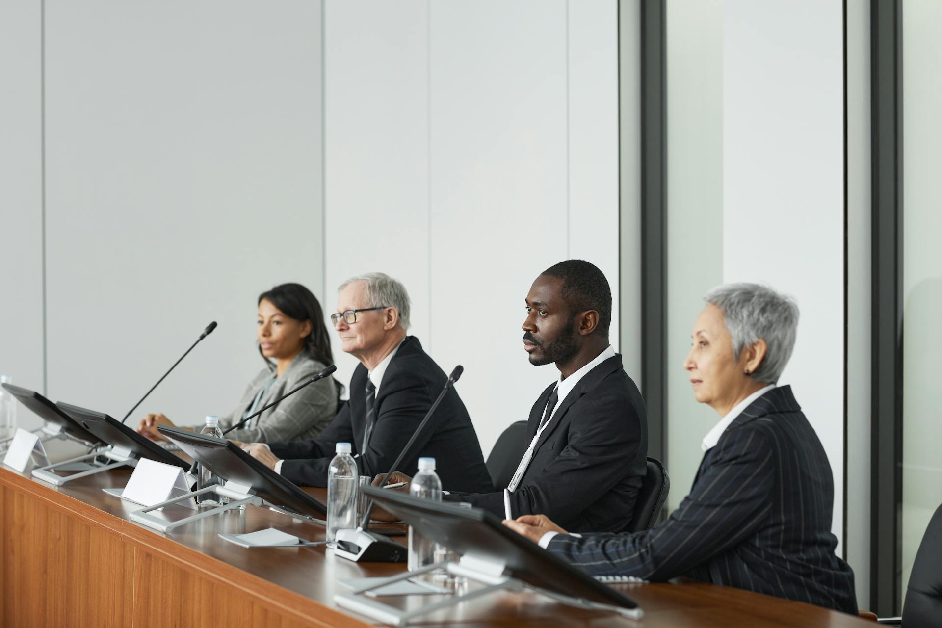 Professional business panel meeting in a modern office setting with four diverse executives seated at a table.