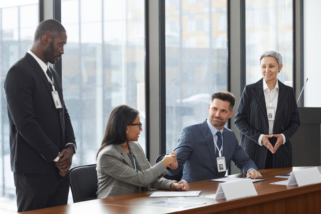 Free A Man and a Woman in Suit Jackets Shaking Hands Stock Photo