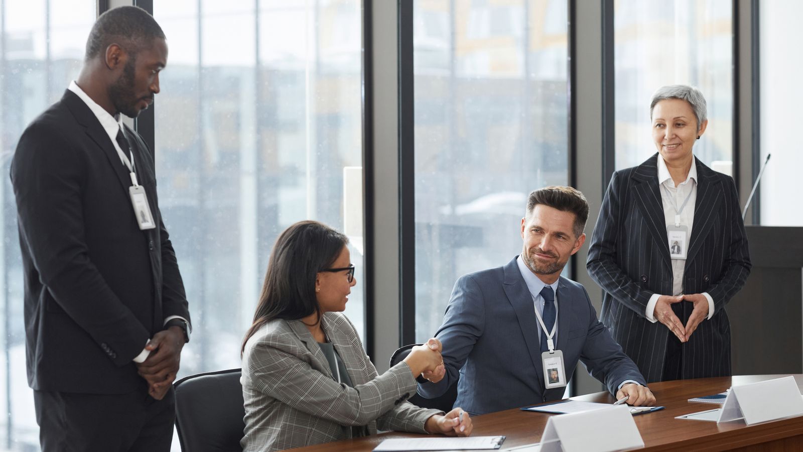 A diverse group of professionals shaking hands during a business meeting in a modern office.