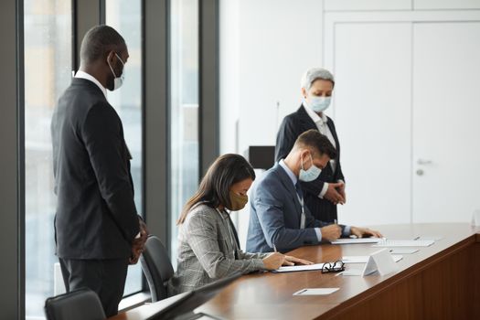 Professionals in a corporate meeting wearing masks for COVID-19 safety protocols.