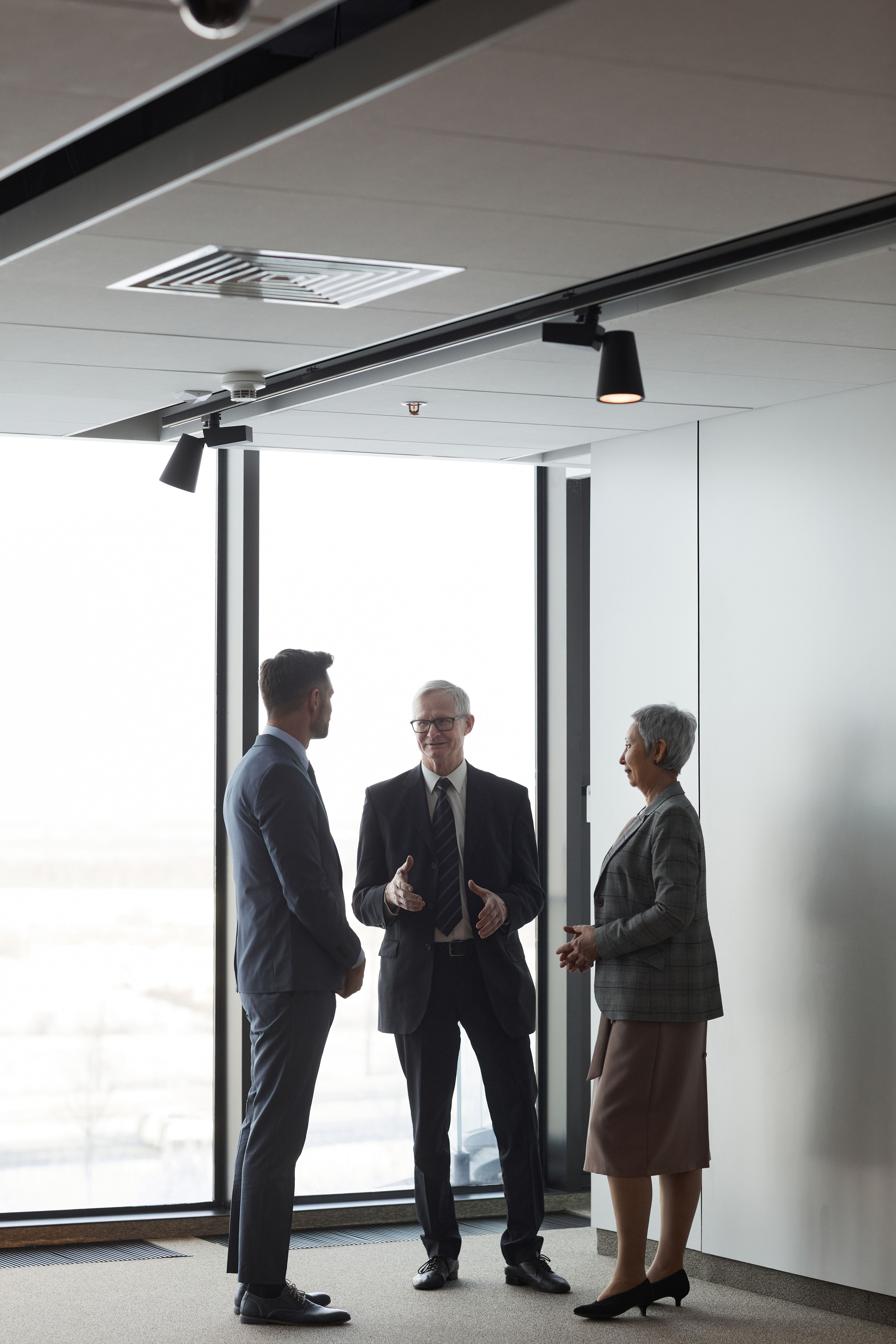 Corporate professionals discussing in a bright modern office setting, highlighting team collaboration and leadership.