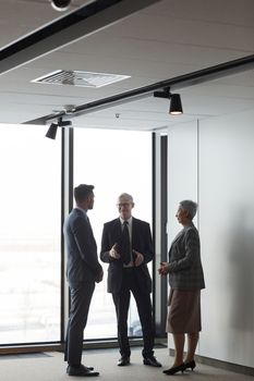Corporate professionals discussing in a bright modern office setting, highlighting team collaboration and leadership.