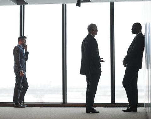 Reunión de asesores impositivos de traje junto a un ventanal de la oficina