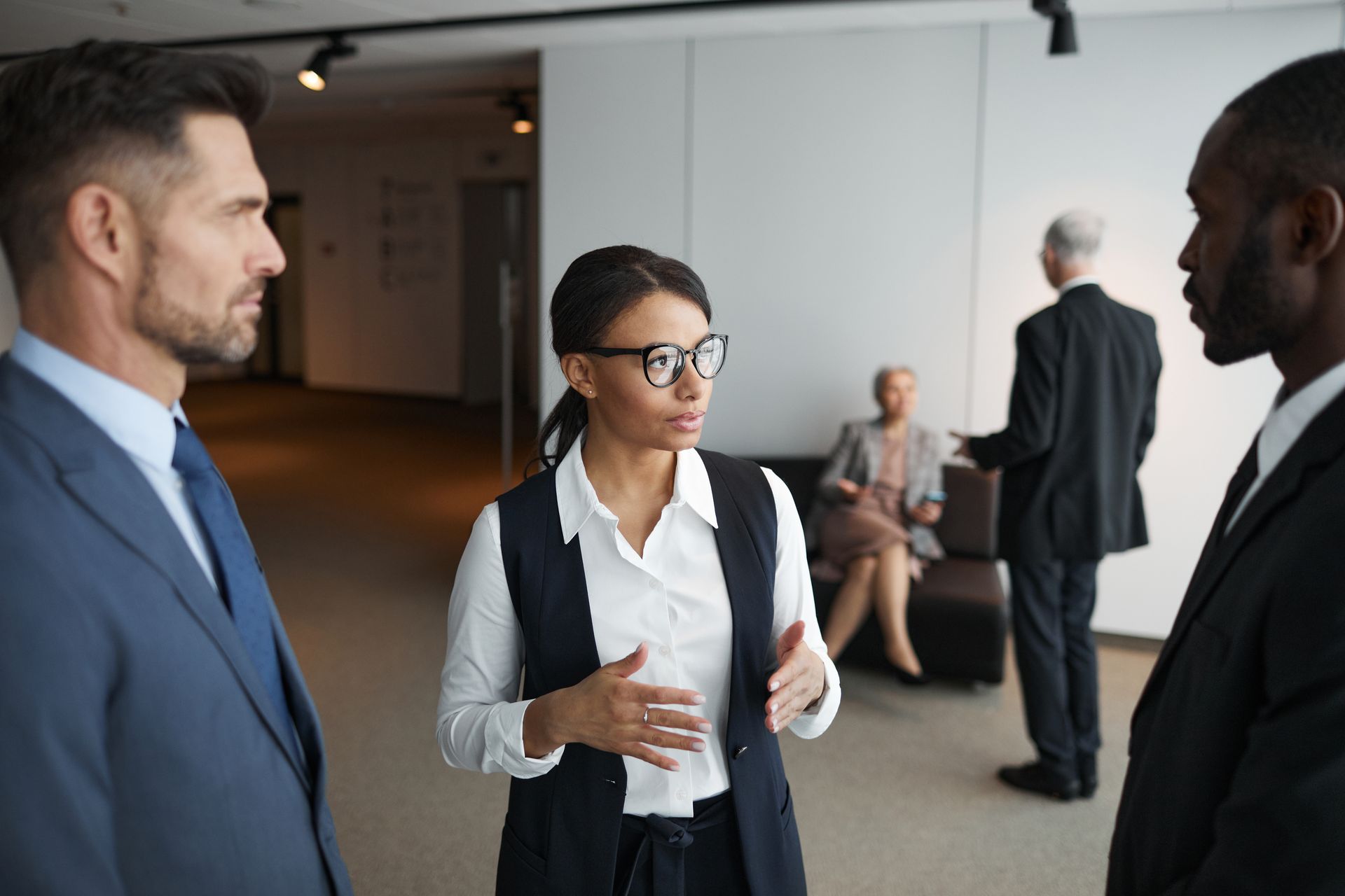 A diverse group of professionals engaged in a serious meeting in an office setting.