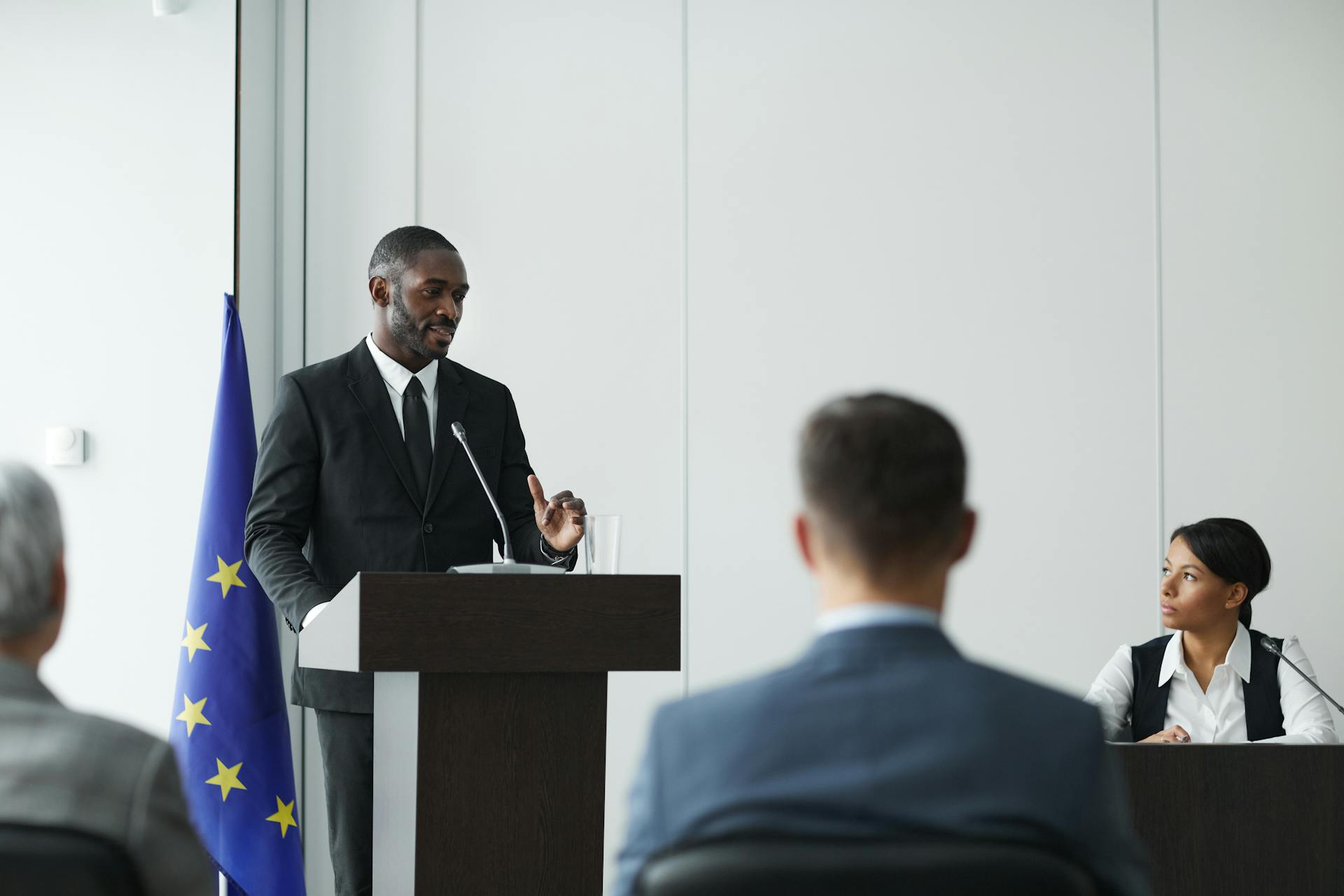 Formal business meeting with diverse speakers in a conference room.