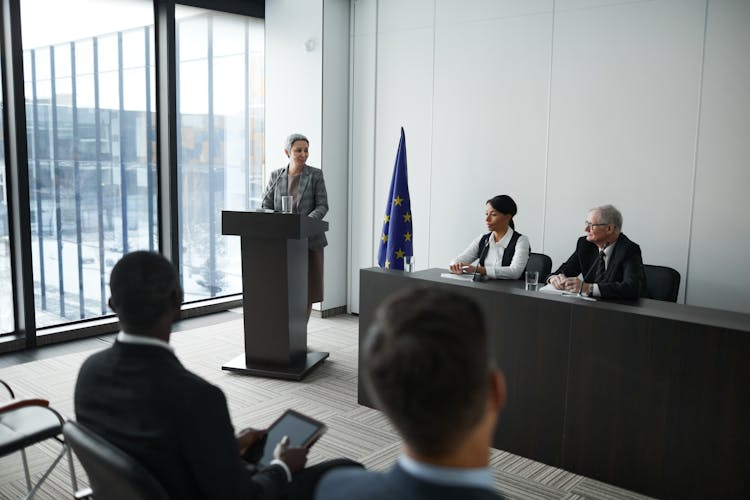 People Listening To The Woman Standing Behind The Podium