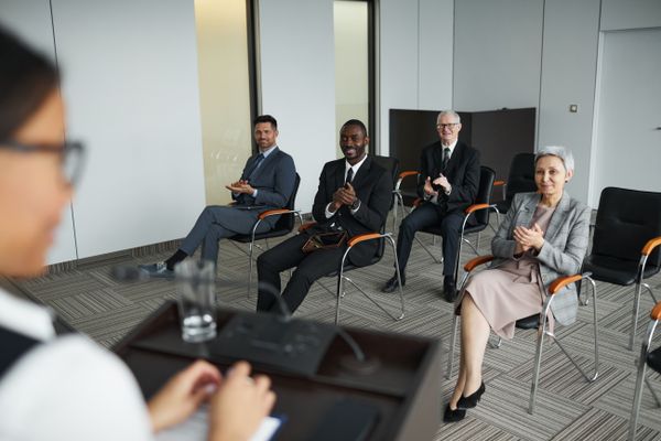 Business audience applauding a speaker at a conference, illustrating the authority a thought leadership program builds