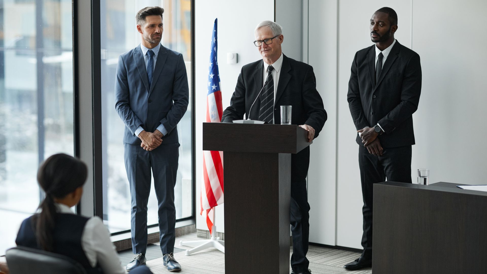 Modafinil for Public Speaking: Unleash Your Oratorical Potential Officials delivering a political speech in a modern conference room with an American flag — modafinil for public speaking