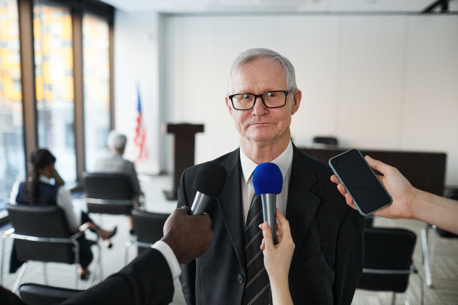 A man in a suit being interviewed in front of microphones