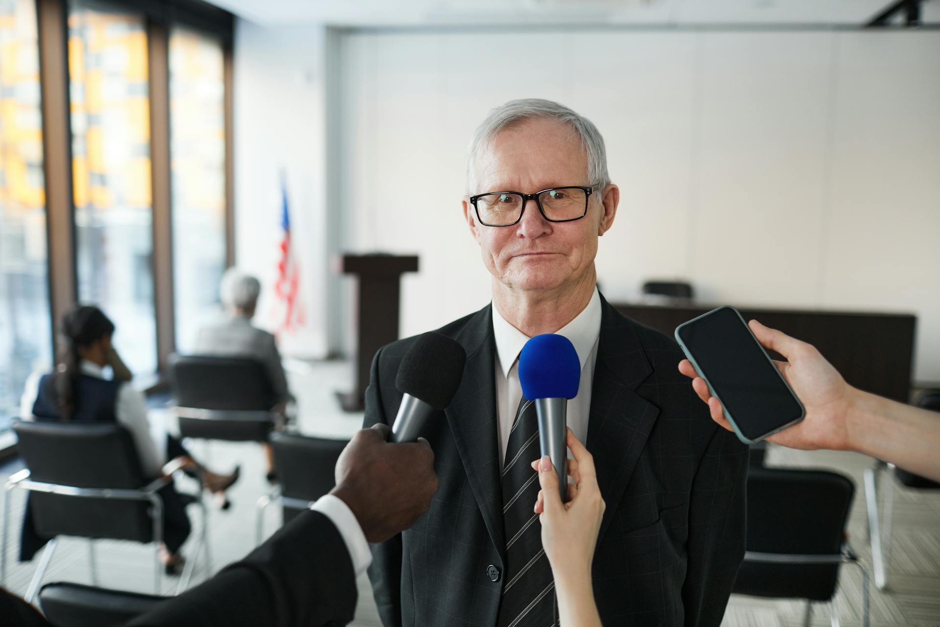 Man in Black Suit Wearing Eyeglasses Being Interviewed by Media