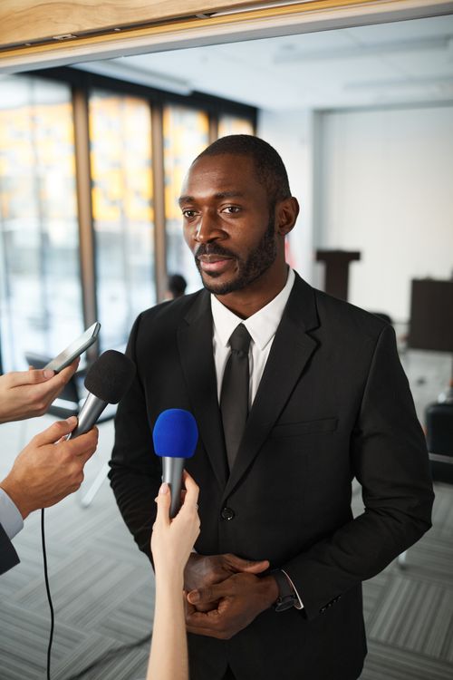 businessman in suit speaking to journalists with microphones
