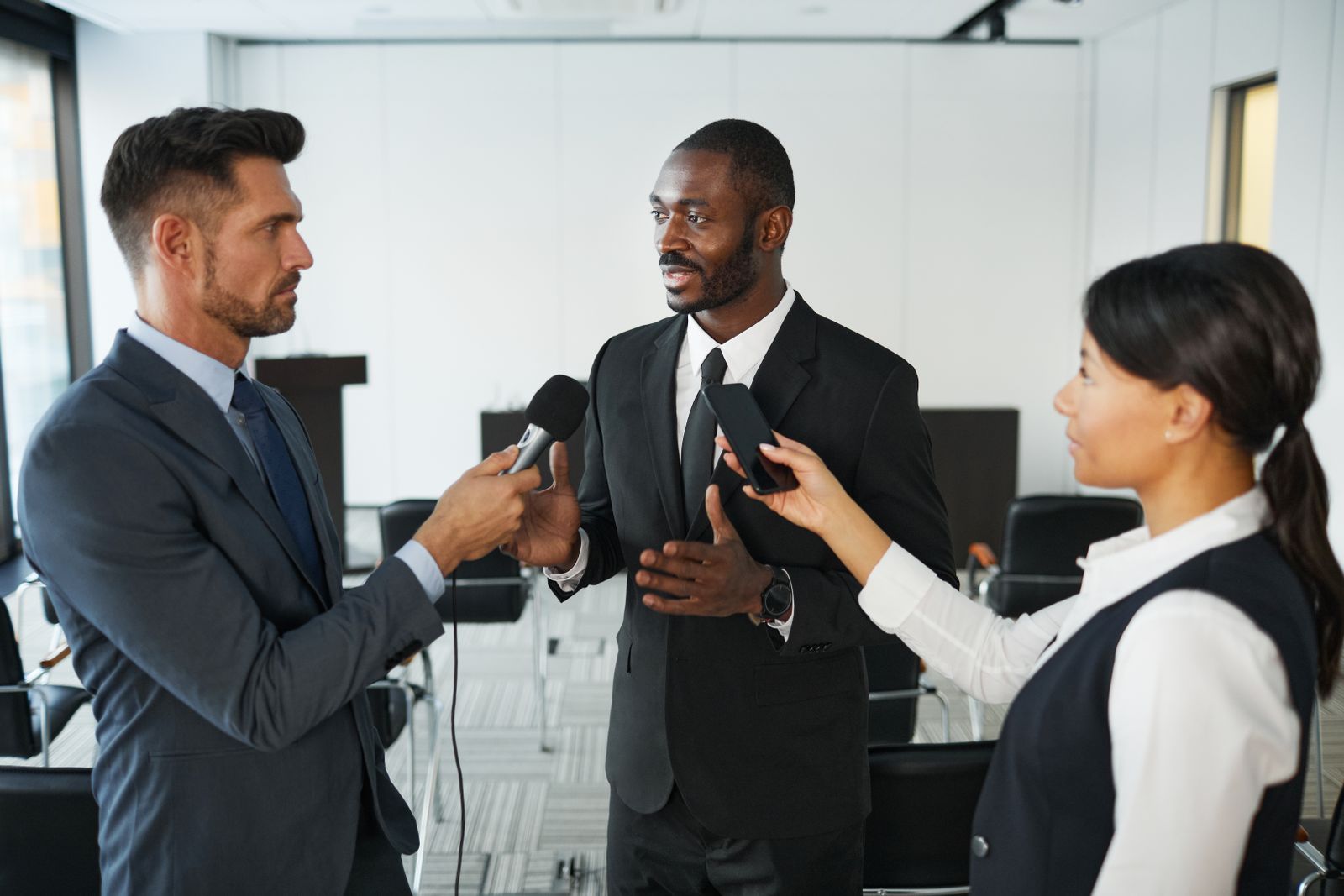 Journalistes tendant leurs micros vers un intervenant lors d'une conférence de presse en entreprise