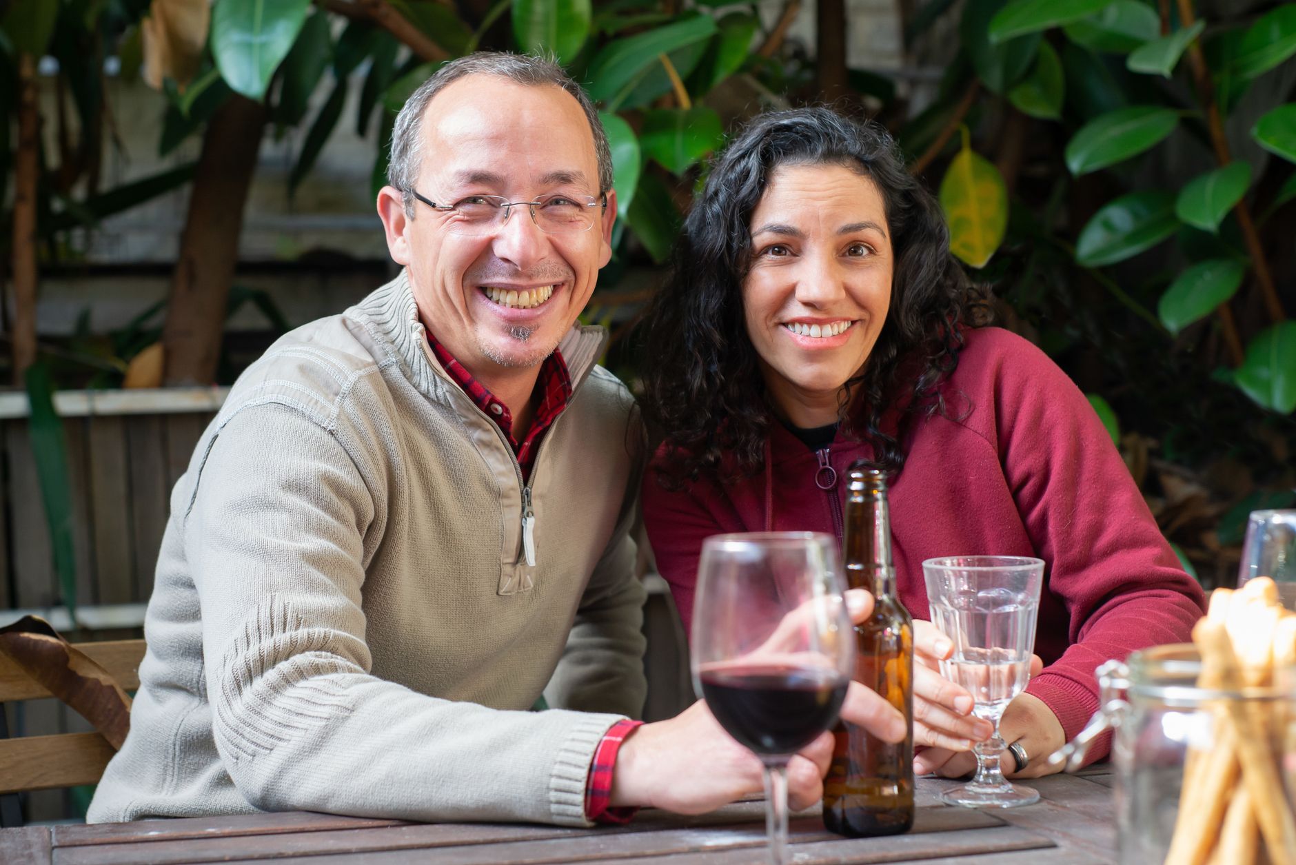 A cheerful couple sitting outside with drinks, enjoying a summer day in Portugal.