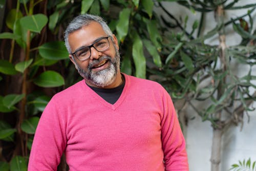 An Elderly Man in Pink Sweater Smiling while Wearing Eyeglasses