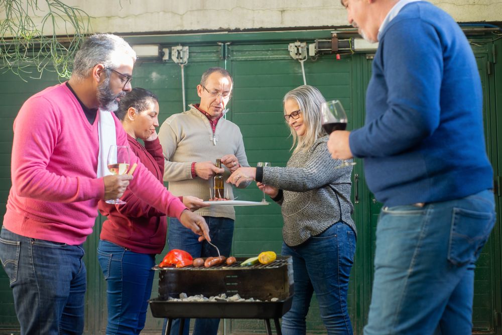 Family and friends gathered around a barbecue with food and drinks