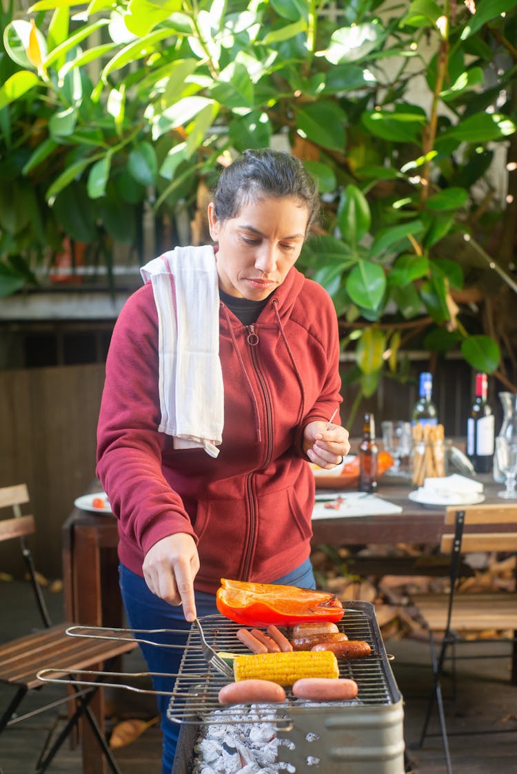 A Woman In Red Jacket Grilling Food