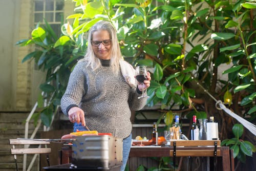 Woman Making a Barbecue While Holding a Glass of Wine