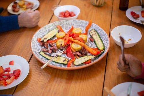 Free A colorful arrangement of roasted vegetables and meat on a dinner table, perfect for sharing and enjoying with family or friends. Stock Photo