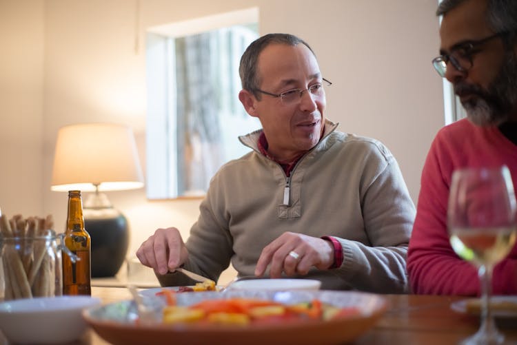 A Man Eating While Talking To His Friend