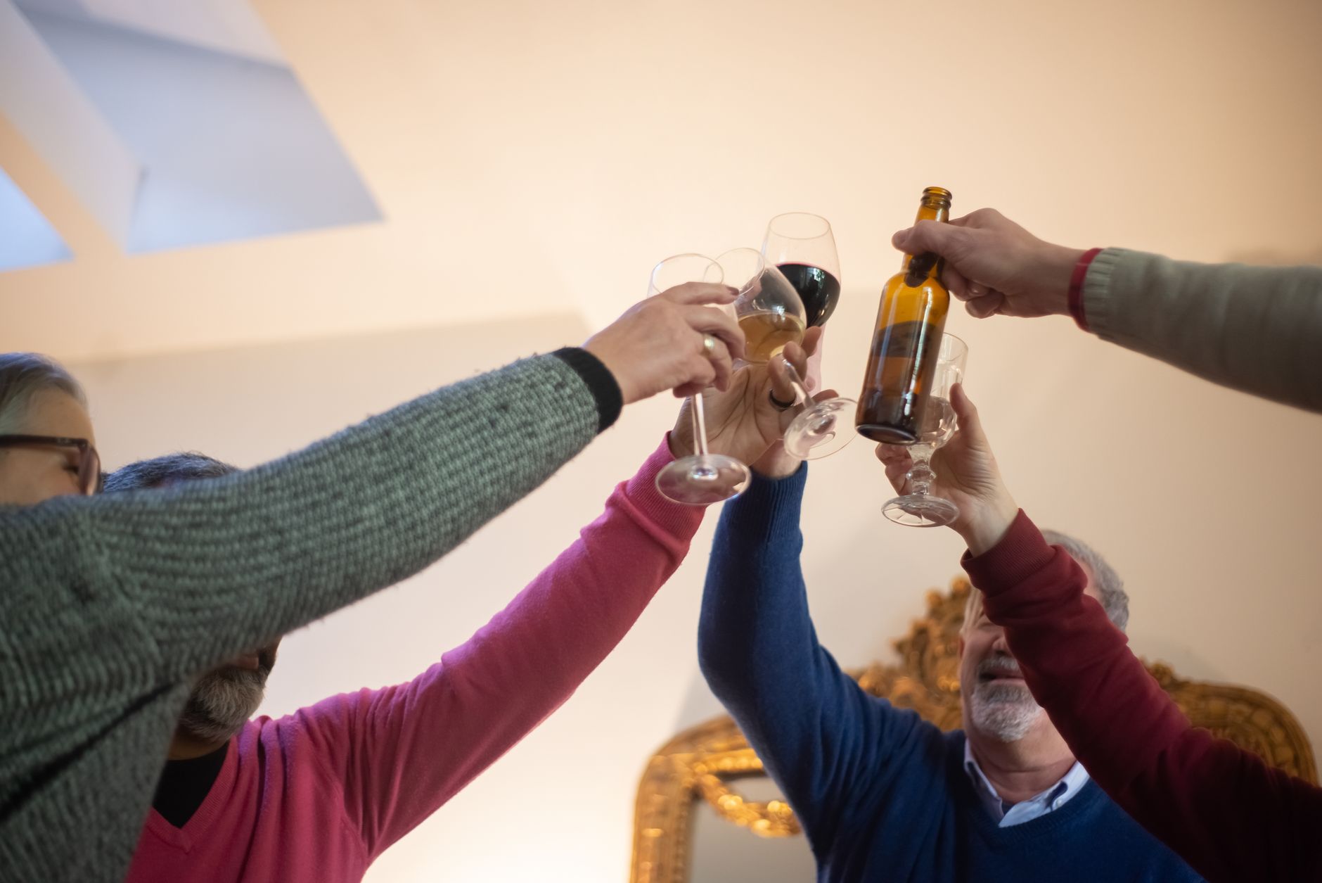 A group of adults raising their glasses in celebration indoors, creating a warm and fun atmosphere.