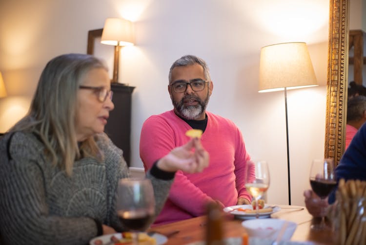 An Elderly Man And Woman Talking While Sitting Near The Table