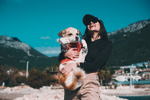 Photo of a Woman in a Black Top Carrying Her White and Brown Dog