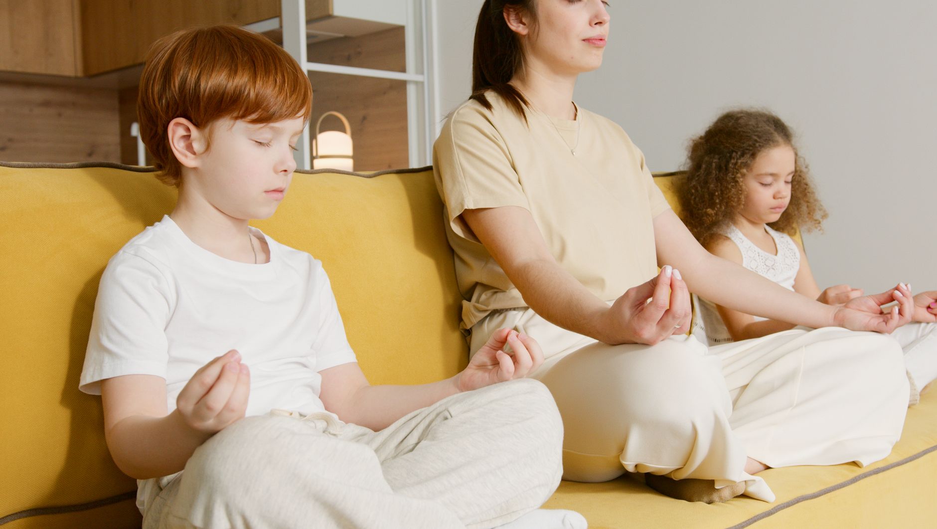 冥想教學兒童靜心:益處、實踐與可能性 Family practicing meditation together on a couch, promoting mindfulness and relaxation.