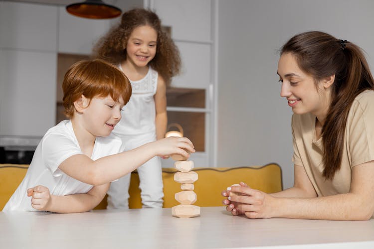 Boy Stacking Pieces Of Stones On A White Table