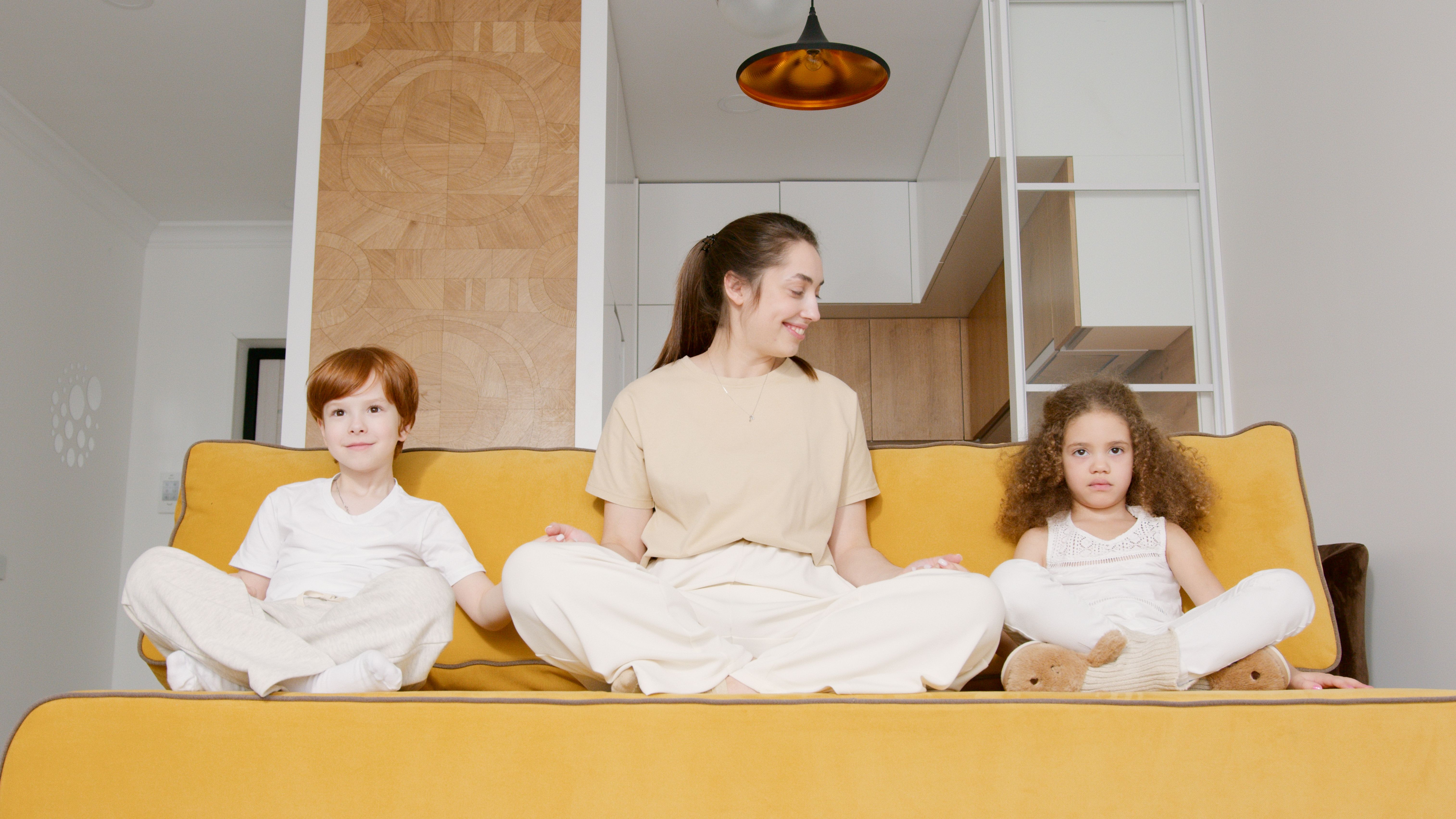 A happy family is relaxing together on a sofa in a bright, comfortable living room, enjoying the perfect indoor temperature. - heat pump replacement granbury tx