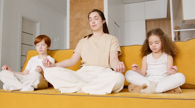 A family enjoying meditation and mindfulness practice together on a yellow couch indoors.