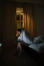 Photo of a Woman Sitting on Her Bed while Watching on a Television