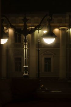 A beautifully lit street lamp at night in front of a classic architectural building.