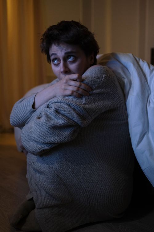 Free Anxious woman sitting alone in dimly lit room, depicting nighttime stress and worry. Stock Photo