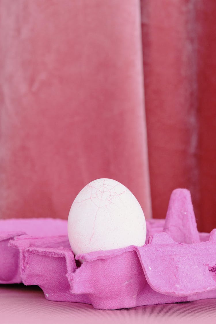 A Cracked Egg On A Pink Egg Tray