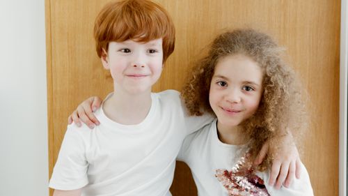 Free Two happy children with arms around each other indoors, showcasing friendship. Stock Photo