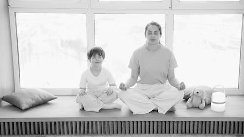 Grayscale Photo of a Woman and Her Son Meditating