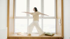A Woman Exercising while Standing on a Windowsill