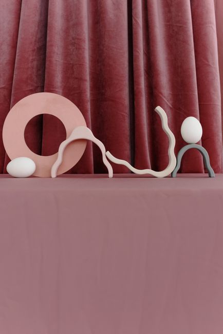 Elegant abstract Easter-themed display with eggs and contemporary decorations against a luxurious curtain backdrop.