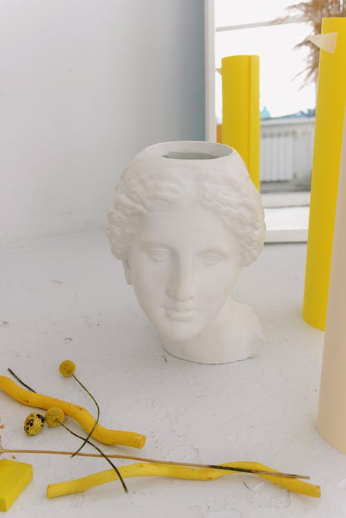 A Pot Headbust Beside Yellow Flowers