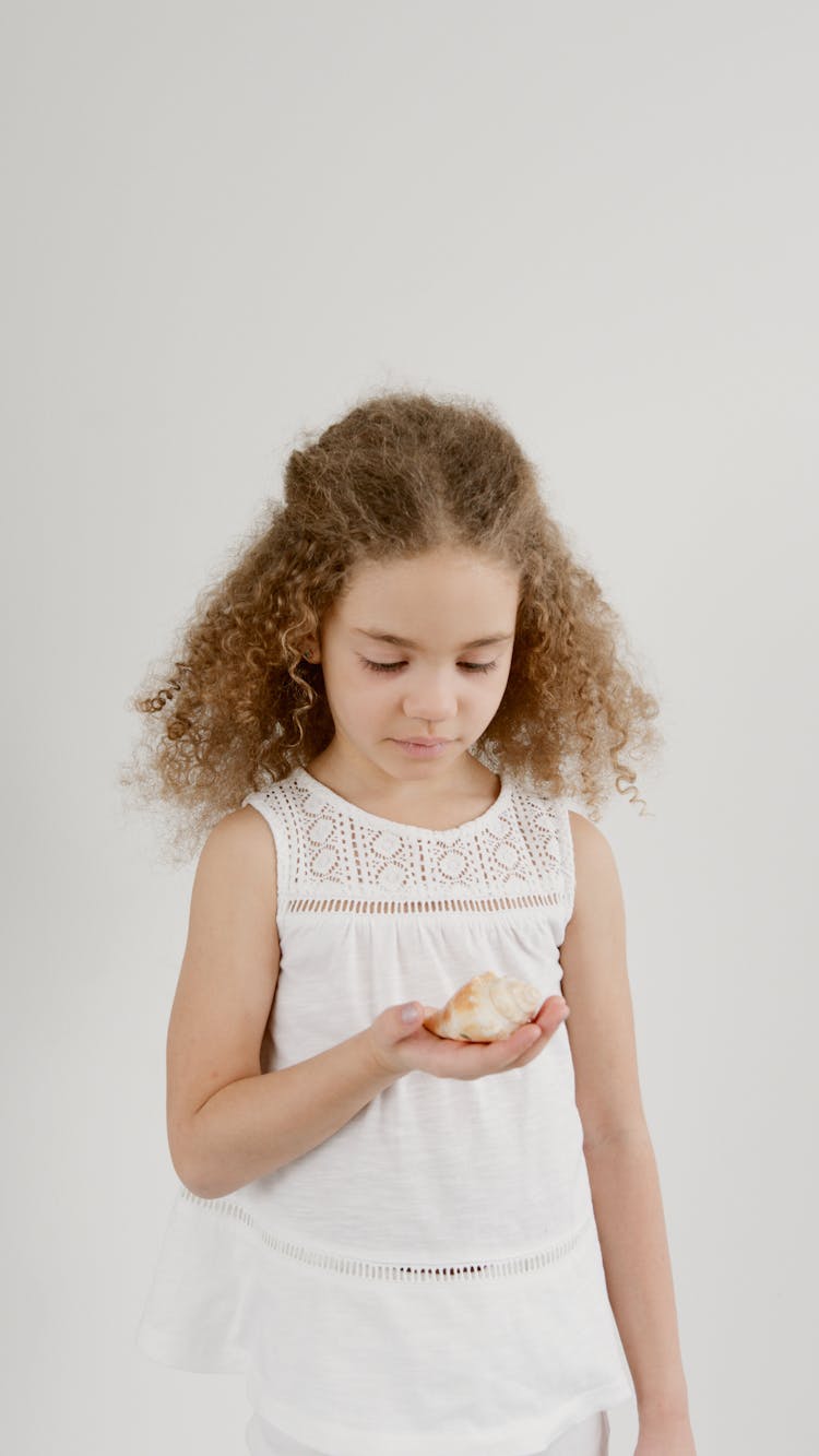 A Young Girl Holding A Seashell