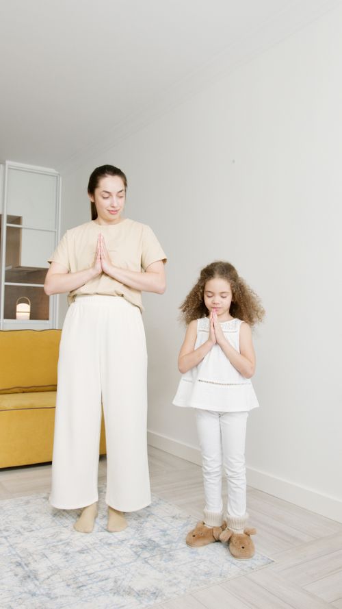 Free A woman and a young girl practicing yoga indoors, promoting wellness and mindfulness. Stock Photo